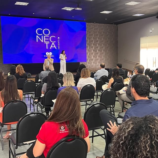 Plateia sentada em evento corporativo Conecta Insights, com palestrantes no palco diante de grande painel de LED e estrutura montada pela GDX Brasil.