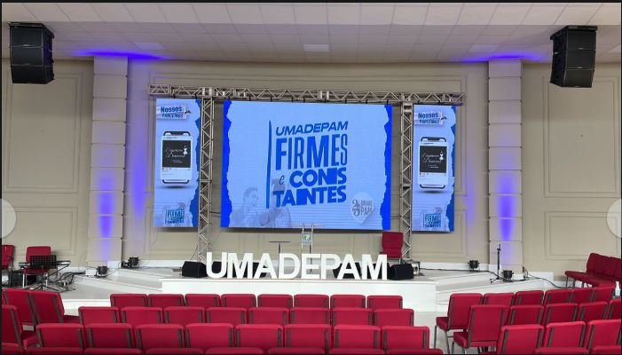 Templo com auditório de cadeiras vermelhas e palco montado pela GDX Brasil, com painel de LED exibindo o congresso UMADEPAM, iluminação e estrutura de treliças.